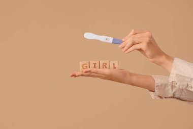 Hamilelik testi olan kadın eller ve bej arka planda 