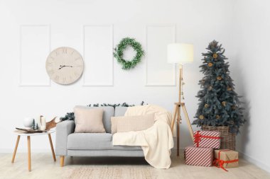 Rahat bir kanepe ve oturma odasındaki beyaz duvarda Noel ökseotu çelengi.