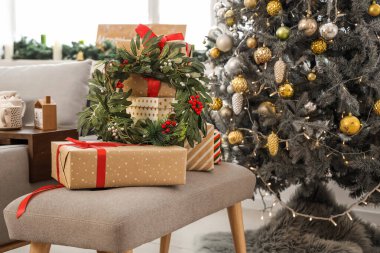 Oturma odasındaki Noel ağacının yanındaki hediye kutularında ökseotu çelengi.