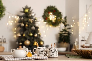 Beyaz duvarında Noel çiçeği çelengi ve masada kakao bardakları olan şık dekore edilmiş mutfağın içi.