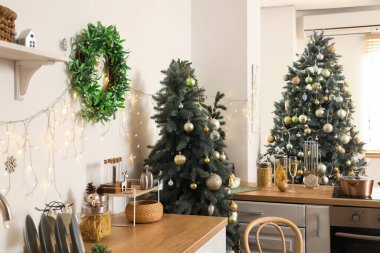 Beyaz duvarında Noel ökse otu çelengi olan şık dekore edilmiş bir mutfak.