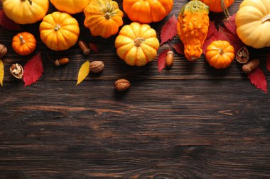 Pumpkins with acorns, walnuts and autumn leaves on wooden background. Harvest festival clipart