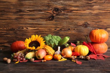 Meyveli farklı taze sebzeler, sonbahar yaprakları ve ahşap arka planda ayçiçeği. Hasat festivali