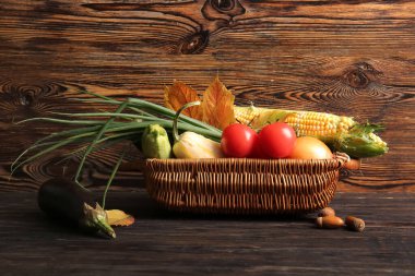 Farklı taze sebzeler ve ahşap arka planda sonbahar yapraklarıyla dolu bir sepet. Hasat festivali