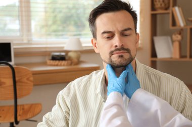 Kadın endokrinolog evdeki tiroid bezini inceliyor, yakın plan.