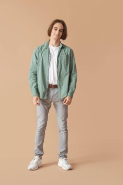 Bej arka planda gülümseyen tişörtlü genç adam.