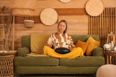 Evdeki kanepede glukofon çalan güzel bir kadın.