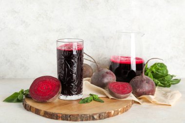 Beyaz arka planda fesleğenli bir bardak taze pancar suyu.