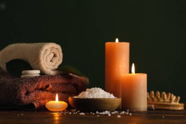 Koyu renk arka planına karşı ahşap masada yanan mumlarla güzel bir spa kompozisyonu