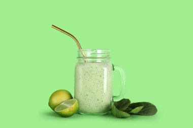 Mason kavanozu yeşil arka planda limonlu ıspanaklı smoothie.