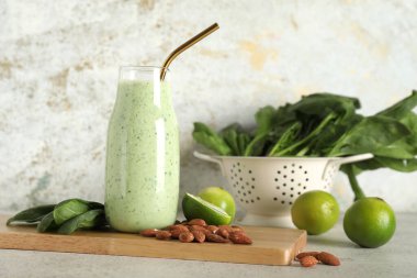 Beyaz arka planda limonlu ve badem fıstıklı bir şişe taze ıspanaklı smoothie.