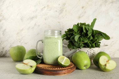 Mason kavanozu beyaz arka planda limonlu ve elmalı taze ıspanaklı smoothie.