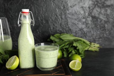 Siyah arka planda limon ve bir şişe taze ıspanaklı smoothie.