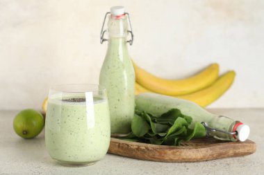 Beyaz arka planda Chia tohumlu, limonlu ve muzlu bir şişe taze ıspanaklı smoothie.