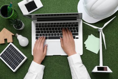 Rüzgâr türbini, güneş paneli ve çimlerin üzerinde ampul kullanan bir kadın. Yeşil Enerji kavramı