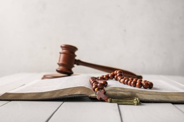 Hafif ahşap masada tespih boncuklarıyla İncil 'i aç