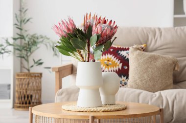 Oturma odasındaki sehpanın üzerinde güzel protea çiçekleri olan vazo.