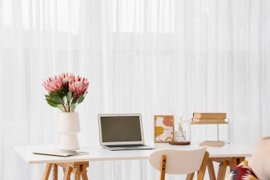 Çalışma odasındaki dizüstü bilgisayarın yanında güzel protea çiçekleri, yakın plan.