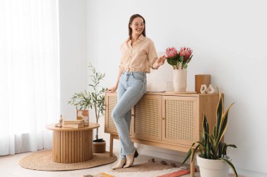 Genç kadın ve protea çiçekleri oturma odasının içinde.