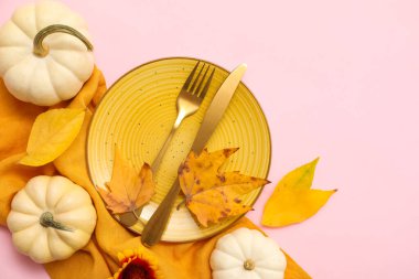 Pembe arka planda taze balkabakları, çiçekleri ve sonbahar yapraklarıyla güzel bir masa.