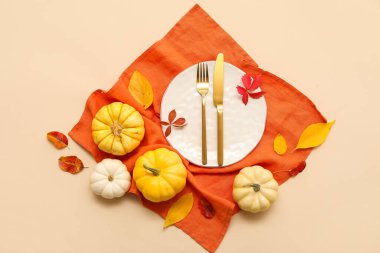 Taze balkabakları ve bej arka planda sonbahar yapraklarıyla güzel bir masa.