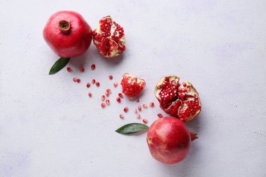 Arkaplanda yapraklar ve tohumlarla taze olgun narlar.