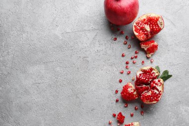 Gri zemin üzerinde tohumları olan taze olgun narlar.