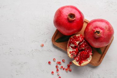 Taze olgun narlar ve beyaz arka planda tohumlarla ahşap tahta.