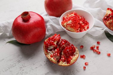 Taze olgun nar ve beyaz arka planda tohumlarla dolu bir kase.