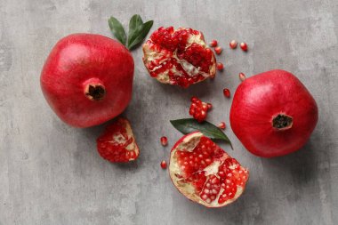 Gri zemin üzerinde yaprakları ve tohumları olan taze nar.