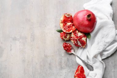 Taze olgun nar ve kaşık, gri arka planda tohumlar.