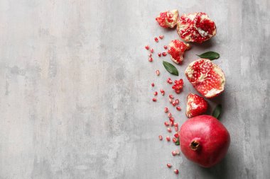 Gri zemin üzerinde yaprakları ve tohumları olan taze nar.