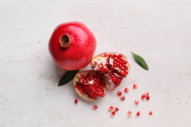 Beyaz zemin üzerinde tohum ve yapraklarla taze olgun nar.