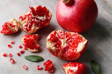 Gri arka planda yaprakları ve tohumları olan taze olgun narlar. Yakın plan.