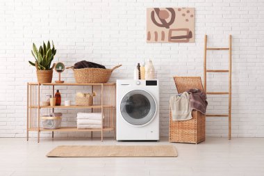 Modern çamaşır makinesi, raf ünitesi, çamaşır ve merdiveni olan sepet