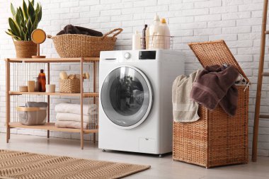 Modern çamaşır makinesi, raf ünitesi ve çamaşır sepeti.