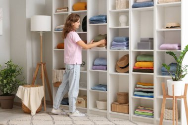 Elbise dolabında kıyafet düzenleyen genç bir kadın.