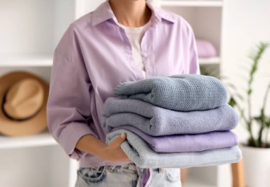 Soyunma odasında kalın kazaklar tutan genç bir kadın. Yakın çekim.