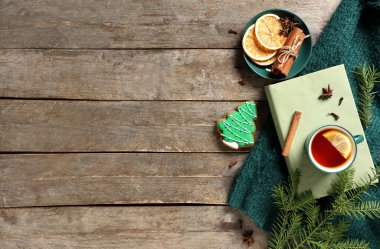 Kitap kompozisyonu, bir fincan çay, baharatlar ve ahşap arka planda sıcak kıyafetler.