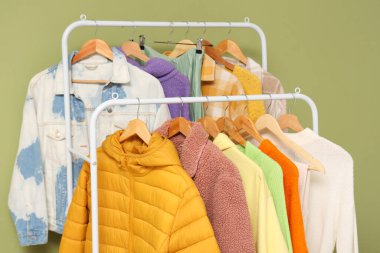 Yeşil duvarın yanında sonbahar giysileriyle raflar