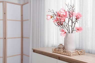 Vazo ve manolya çiçekleri. Odadaki çekmecelerin üstündeki tepside.