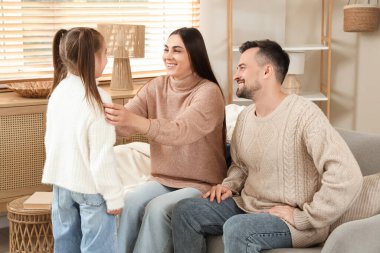 Evdeki koltukta oturan kızlarıyla mutlu bir aile.
