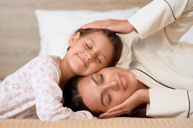 Annesini küçük kızıyla yatak odasında kucaklamak, yakın çekim. Uluslararası Sarılma Günü