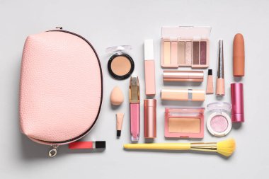 Gri arkaplanda farklı makyaj ürünleri bulunan kozmetik çanta