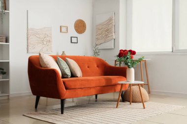 Rahat bir kanepe ve kahve masası. Oturma odasında vazoda yıldız çiçekleri var.