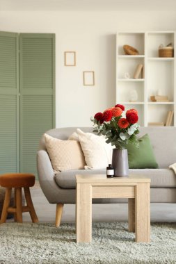 Oturma odasının iç tarafındaki rahat kanepenin yanındaki kahve masasında Dahlia çiçekleri.