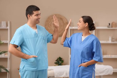 Masaj terapistleri spa salonunda birbirlerine beşlik çakıyorlar.