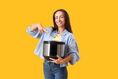 Sarı arka planda çoklu fırını gösteren güzel bir kadın.