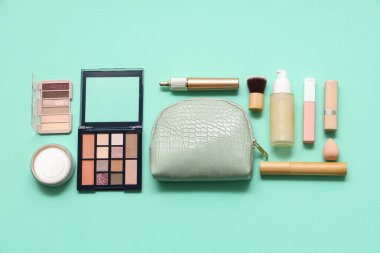 Yeşil arka planda kozmetik çanta ve makyaj ürünleri
