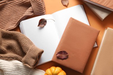 Kitaplı kompozisyon, kalın giysiler ve arka planda düşmüş yapraklar